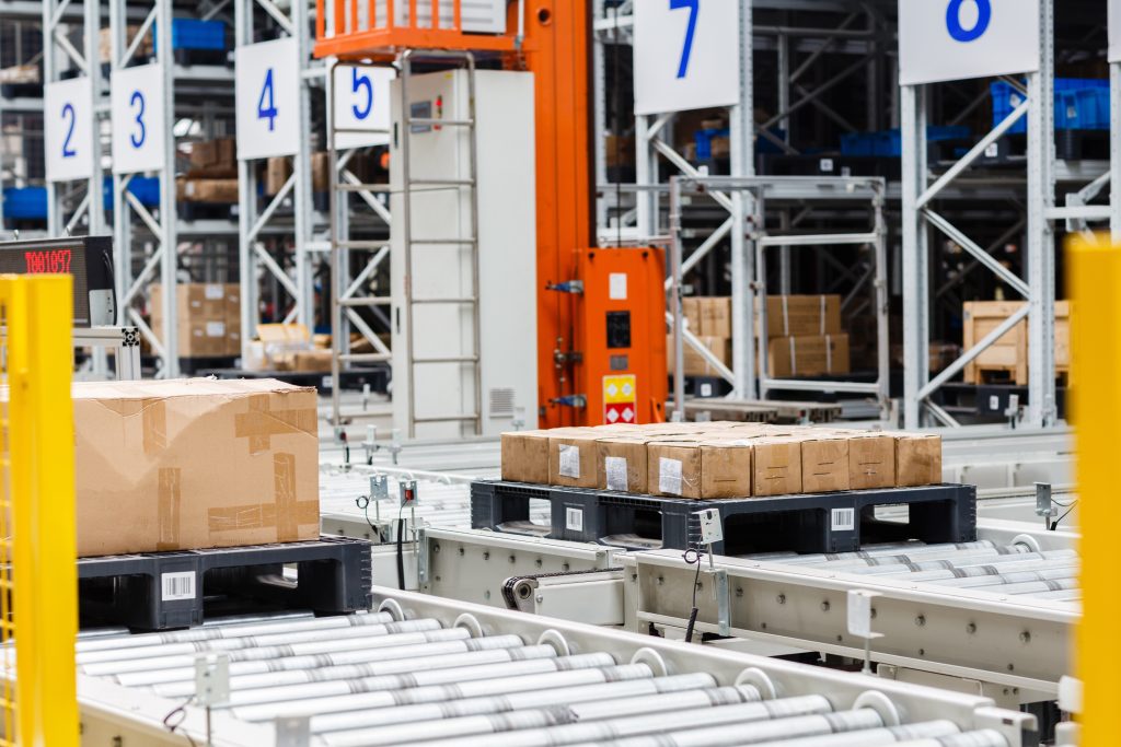 Logistics conveyor system transporting boxed goods in a warehouse facility.